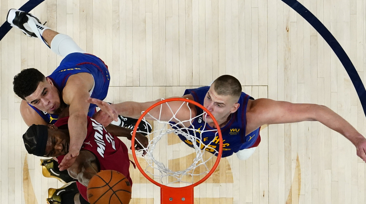 Miami Heat forward Jimmy Butler (22) shoots the ball against Denver Nuggets forward Michael Porter Jr. (top) and center Nikola Jokic (right) during the second half in game one of the 2023 NBA Finals.